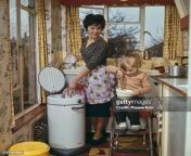 a mother places wet clothes in a portable spin dryer as a young girl sits on a stool holding jpgs612x612wgik20csz568vbt84xbdthetcp770kxawexdrroxdmlijltask from kitchen mom young gurls reyal