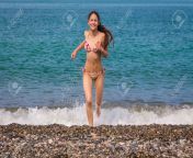 59663105 happy young girl running from sea on beach with pebbles.jpg from teen nudist