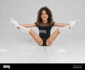 young female professional gymnast sitting on floor with legs wide up isolated on gray studio background smiling girl in black sportswear and knee socks with curly hair showing flexibility 2bm7n5e.jpg from cumonprintedpics jb knees
