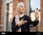 young smiling happy muslim woman doing video call using smartphone at the city arabian woman blogger wearing hijab speaking on the smart phone with her audience walking in the street 2jfx5mj.jpg from hijabi gf selfshot video getting naked for bf