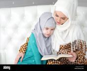 muslim mom in white hijab and traditional clothes is reading for her little daughter a book and cuddling her sitting on the sofa at home in white modern interior t8nyy5.jpg from mom muslim veil