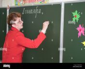 female old russian teacher near the green blackboard is writing be3hkd.jpg from teacher russian