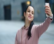 videoblocks close up smiling woman waving hand to smartphone camera happy girl using mobile phone for video chat outdoor portrait of cheerful woman call video online at urban street r9allor0h thumbnail 1080 01.png from a and her smartphone camera